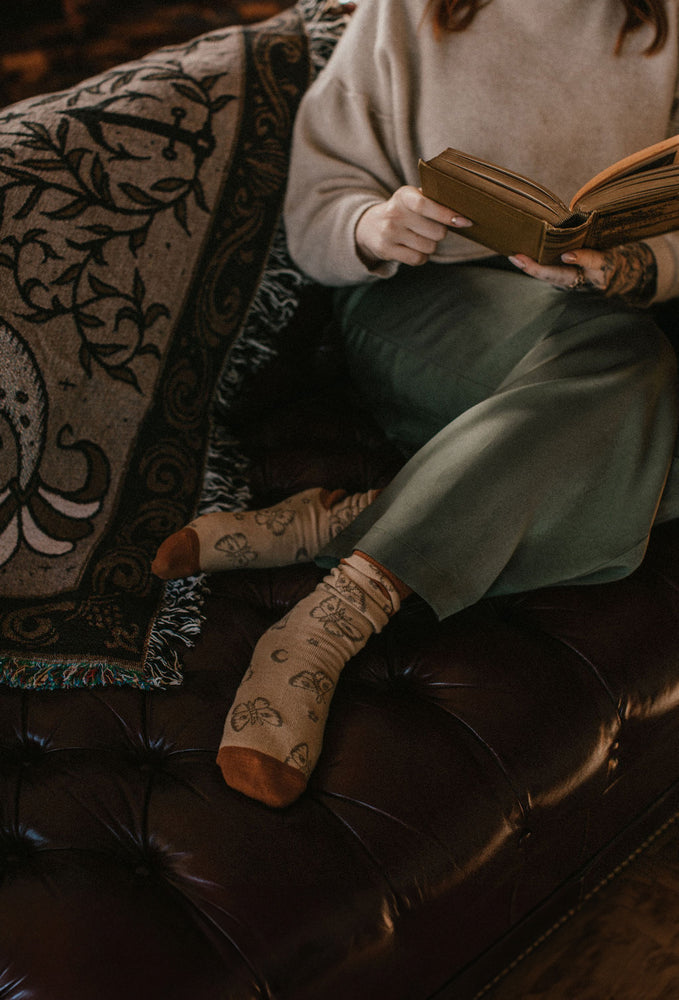 A woman wearing a cozy pair of socks woven with a moth and moons pattern for cottage core style. 