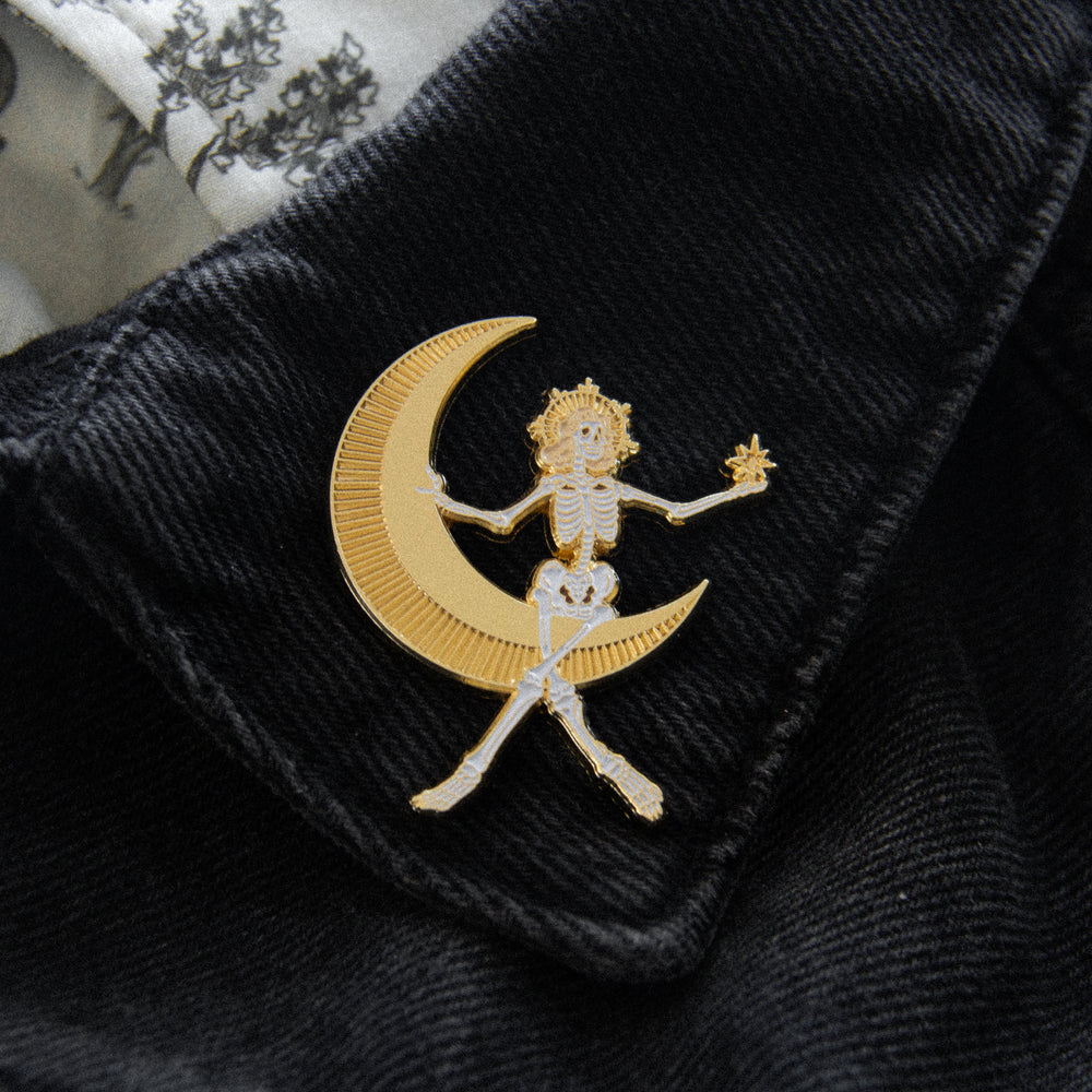 A fashion accessory brooch of a vintage film, hollywood glamour inspired pin of a woman sitting in the moon. 