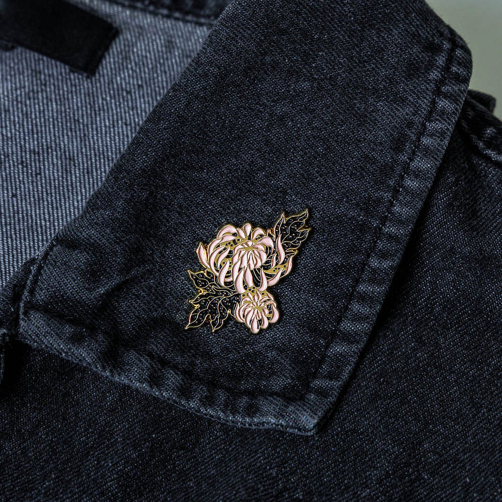 A botanical chrysanthemum flower accessory on the lapel of a denim jacket for women's fashion.