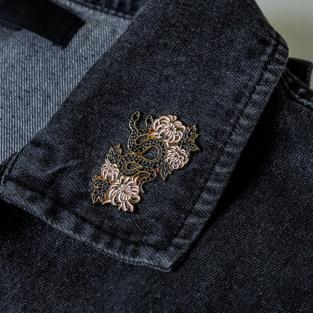 A beautiful lapel pin of a snake with florals on a denim jacket. 