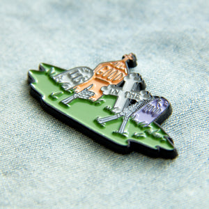 A funny Halloween enamel pin of tombstones with happy skeletons. 