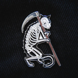 Ectogasm grim reaper cat enamel pin, featuring a skeleton cat holding a scythe in black, silver, and white. 