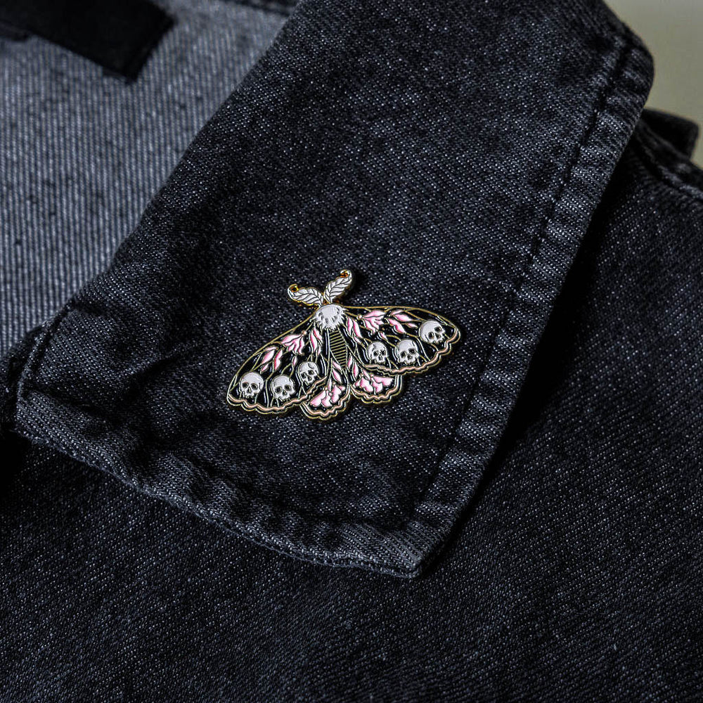 A moth insect pin on the lapel of a denim jacket for alternative and gothic fashion. 
