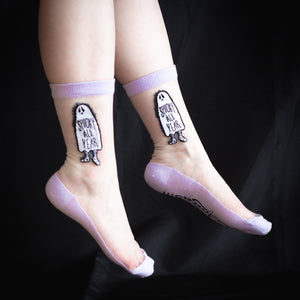 Witchy see-through socks in lavender, black, and white. On the side of the socks is a ghost with the funny quote, "Spooky All Year", for Halloween inspired fashion. 