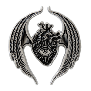 A gothic style brooch featuring an oddities and curiosities inspired design of an anatomical heart with bat wings and an all seeing eye. 