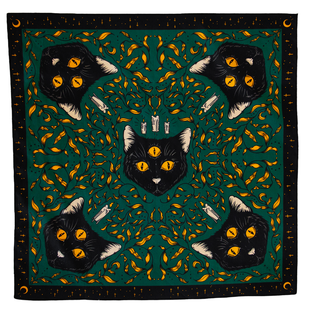 A bandana or altar cloth with a witchy pattern of black cats on a green background, surrounded by gold leaves. Boarder has stars and moons for gothic and alternative fashion. 