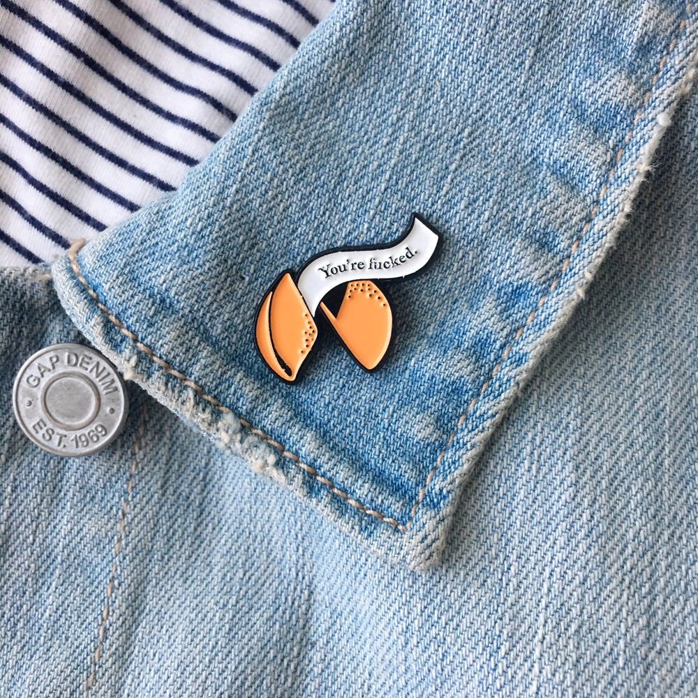 A funny fortune cookie enamel pin on a jacket lapel. 