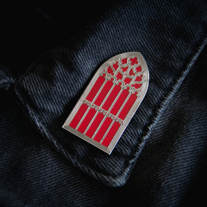 Red and silver witchy brooch on the lapel of a denim jacket for alternative fashion. 