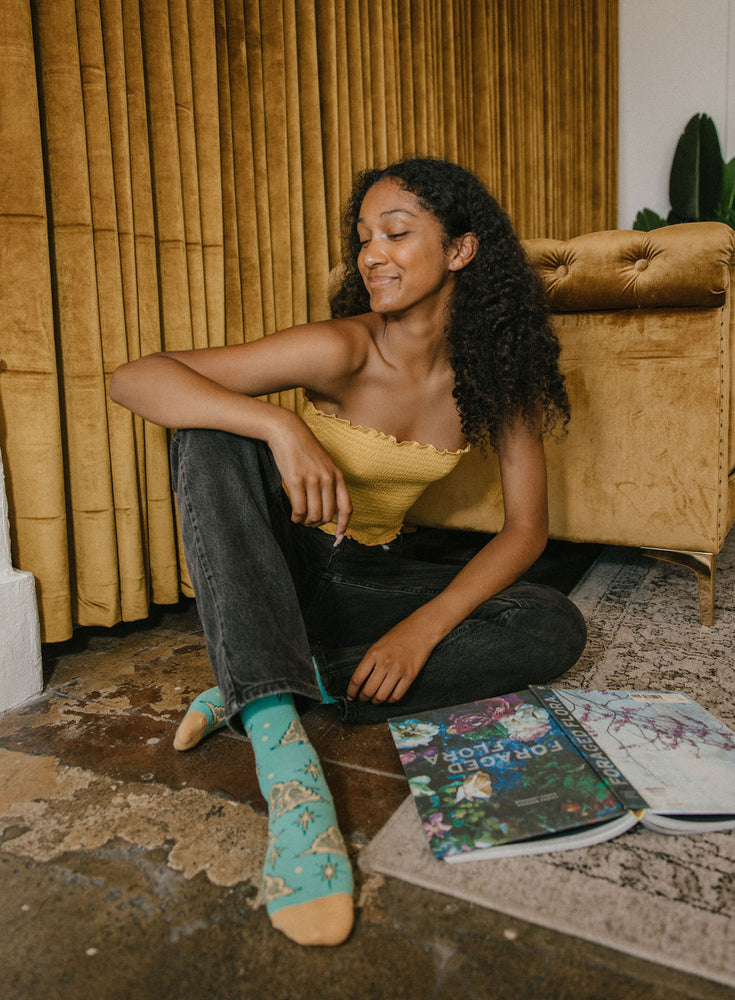 A woman wearing comfy blue and yellow socks with stars and moons on them for loungewear style. 