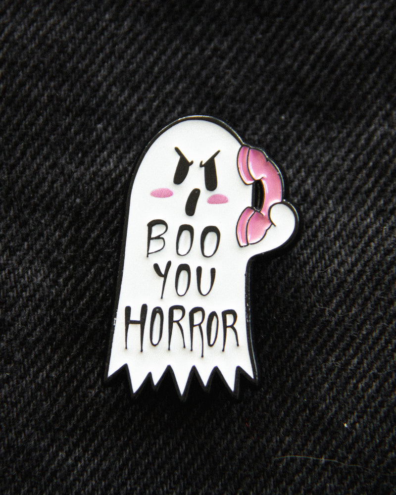 A funny ghost lapel pin in black, white, and pink, with the 90's movie quote, "boo you horror", for alternative fashion and Halloween style. 