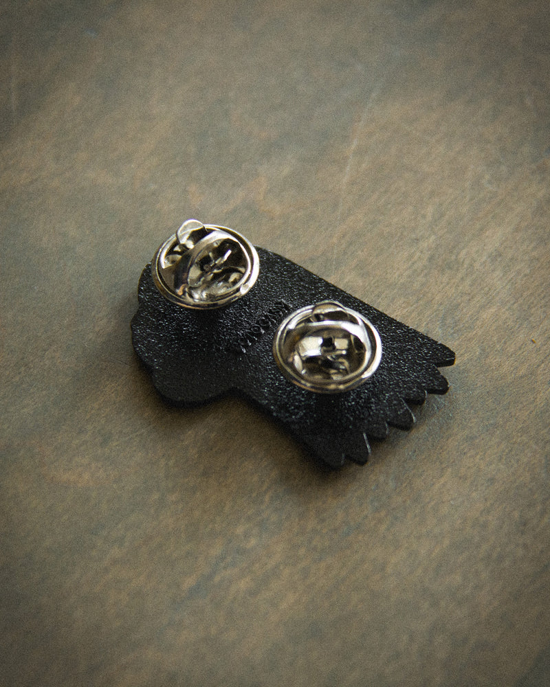 Clasps on the back of a black Ectogasm enamel pin. 