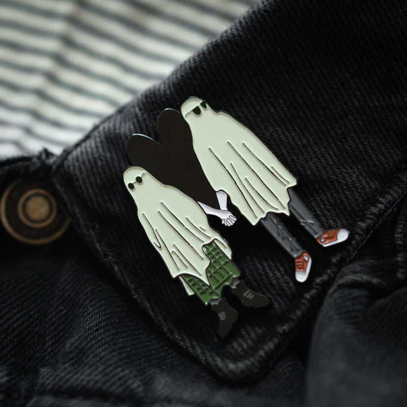 A dark romance lapel pin of a ghost boyfriend and girlfriend holding hands. 