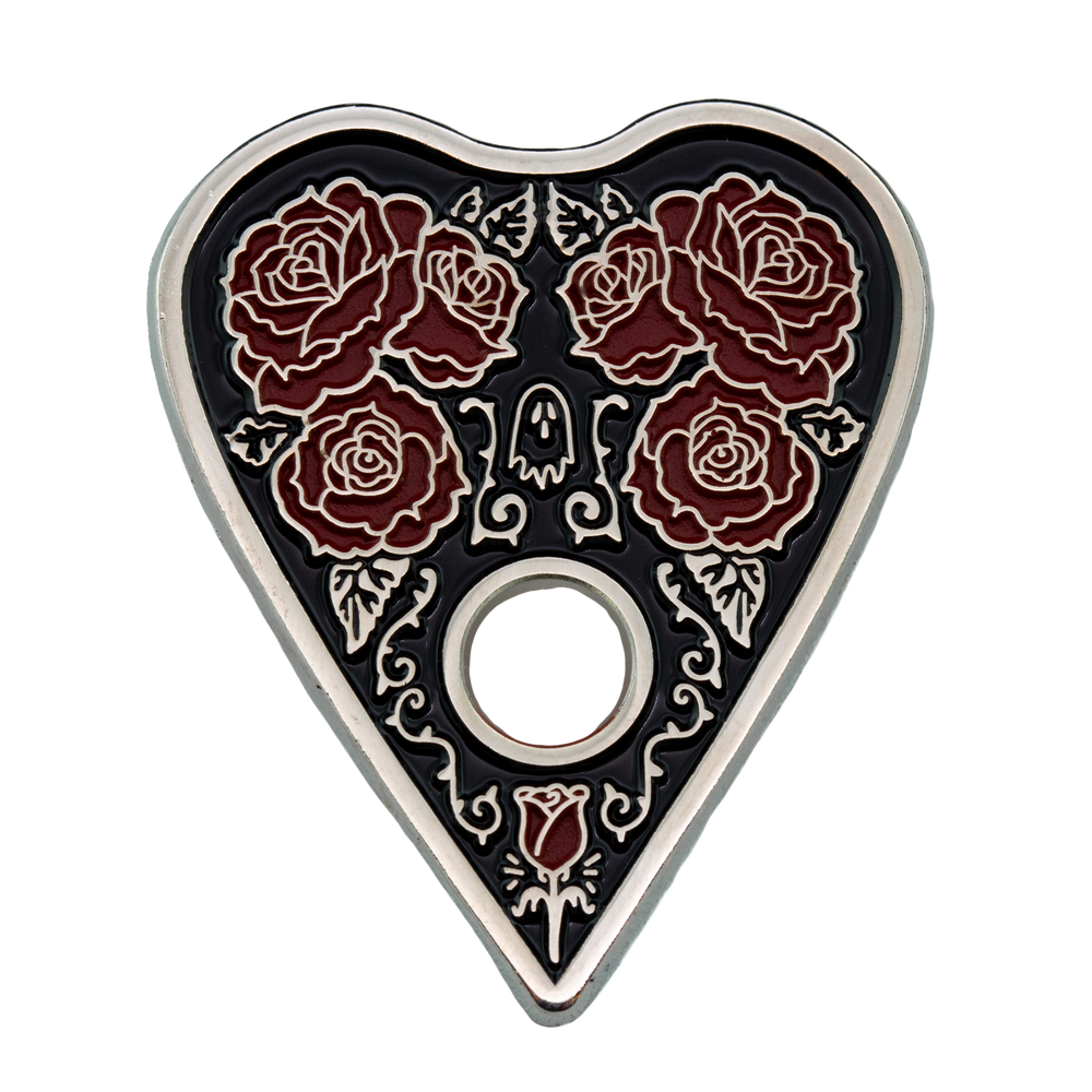 A gothic style enamel pin of a ouija planchette wih roses. 