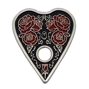 A gothic style enamel pin of a ouija planchette wih roses. 