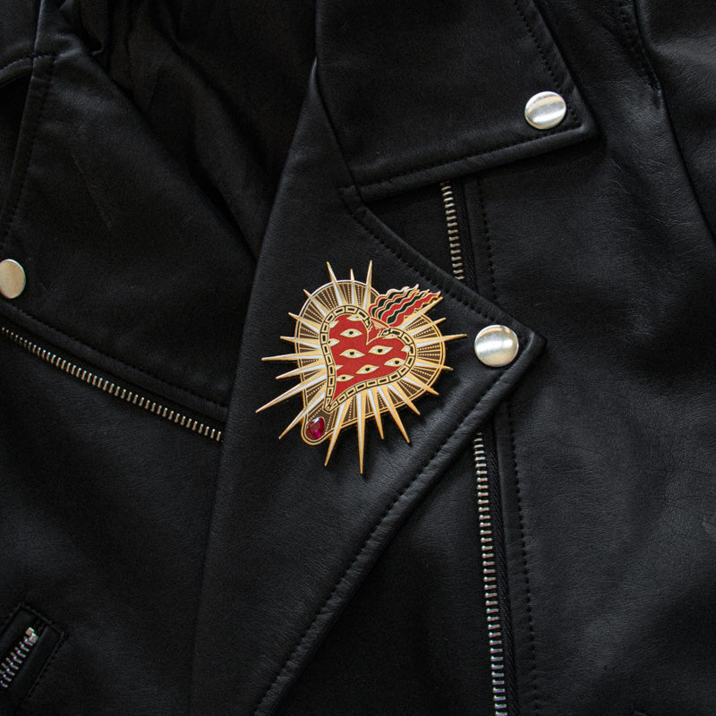 Rock and roll high end luxury punk fashion brooch of a flaming heart on the lapel of a leather jacket for men's and women's all gender jewelry.