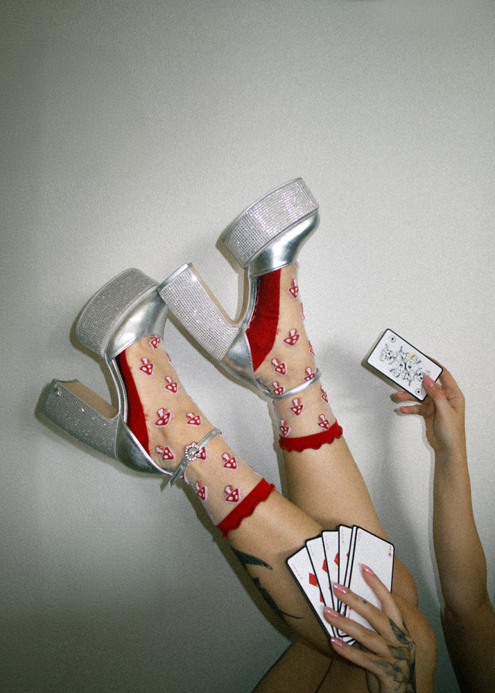 An alternative fashion woman wearing heels with ruffled sheer shrooms socks in red and white. 