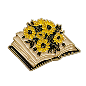 A cute enamel pin of an open book blooming with sunflowers. 