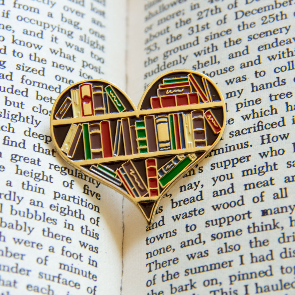 A literature themed enamel pin inside of a book. 