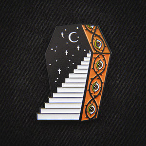 A metaphysical enamel pin of a coffin with a stairway leading into it. Designed by Ectogasm.