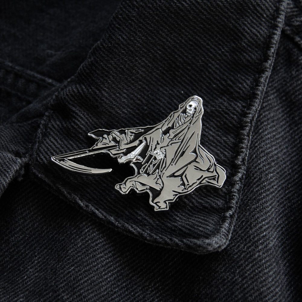 Black and silver grim reaper enamel pin for punk and metal fashion.