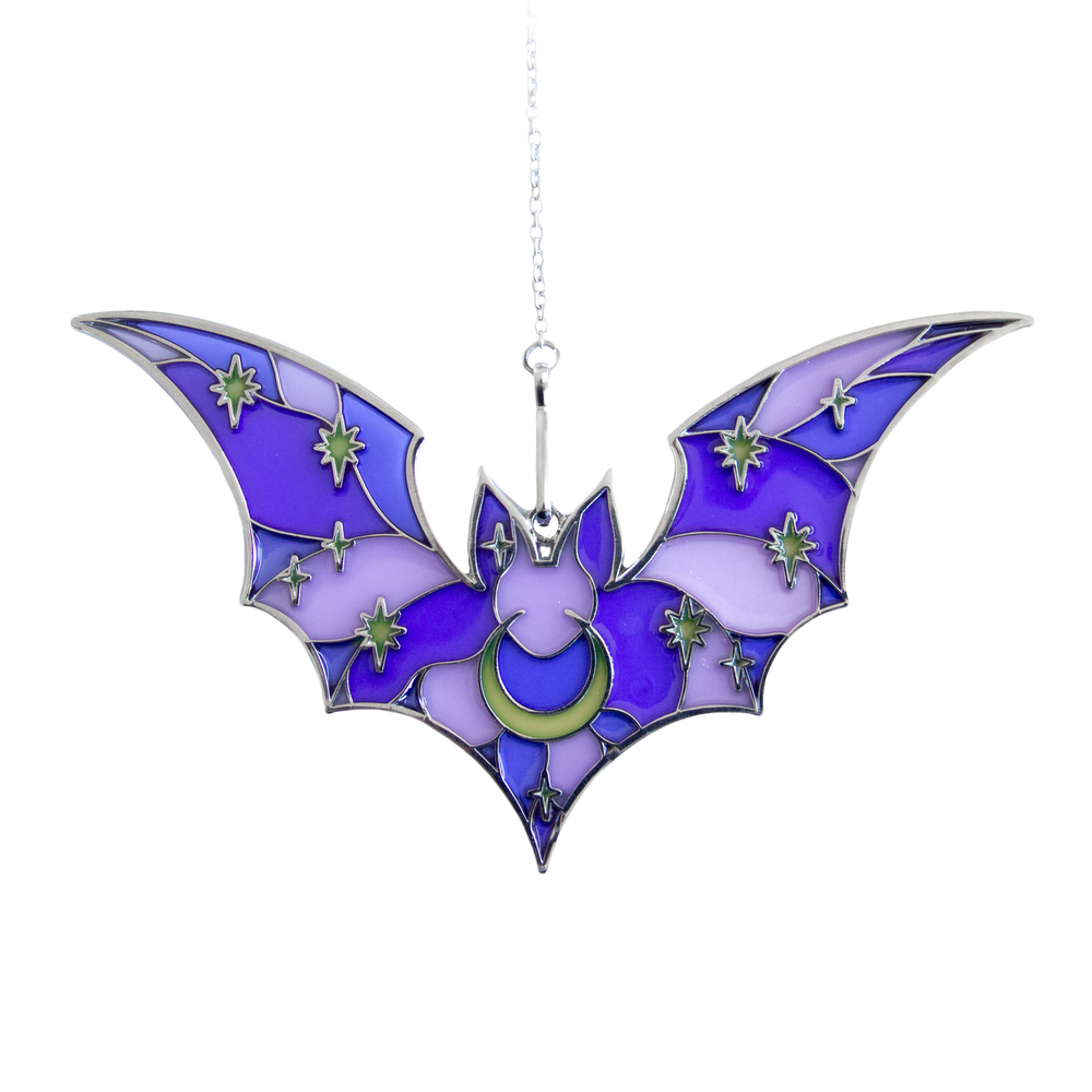 A silver, purple, and yellow stained glass suncatcher shaped like a bat with stars and a moon. 