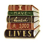 An enamel pin of a stack of books with the quote, "I have lived one thousand lives. 