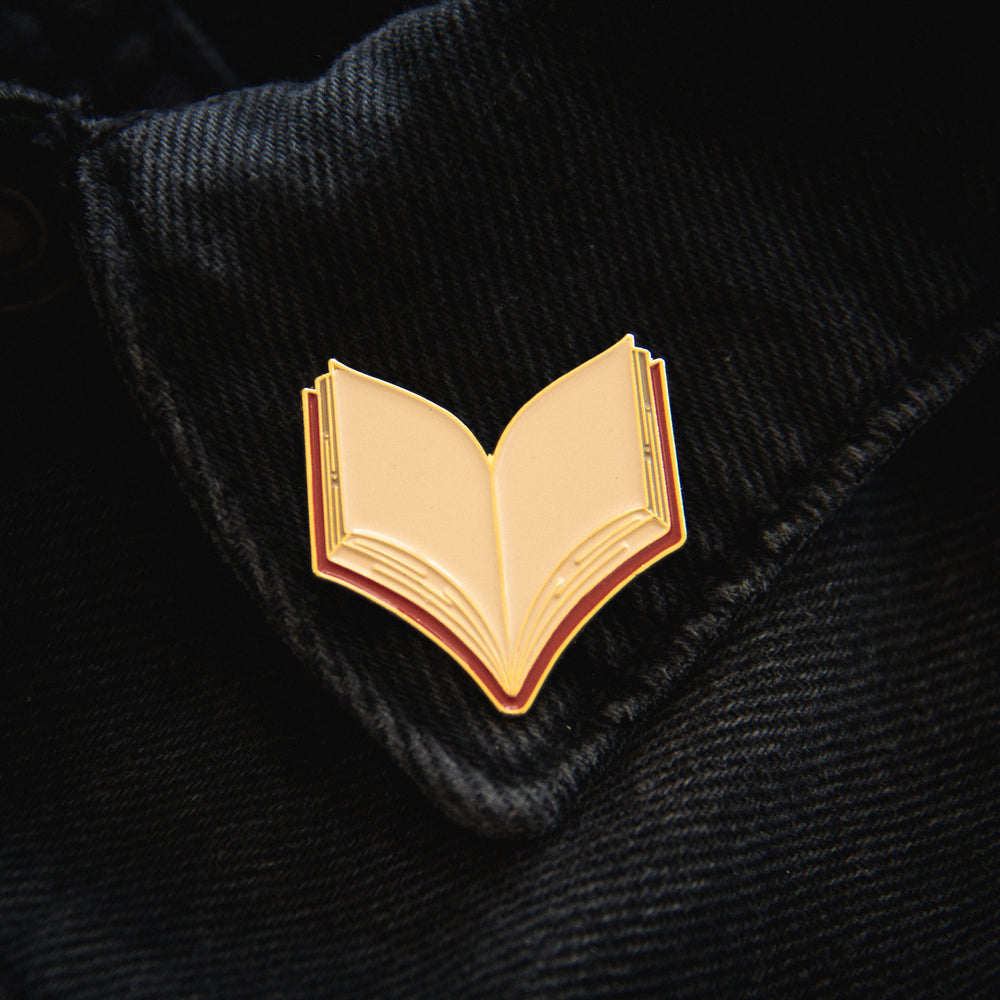 A red and gold book lapel pin for librarian style. 