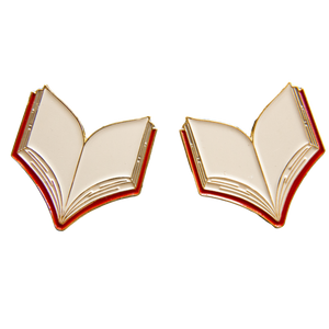 A lapel pin of an open book in gold and red. 