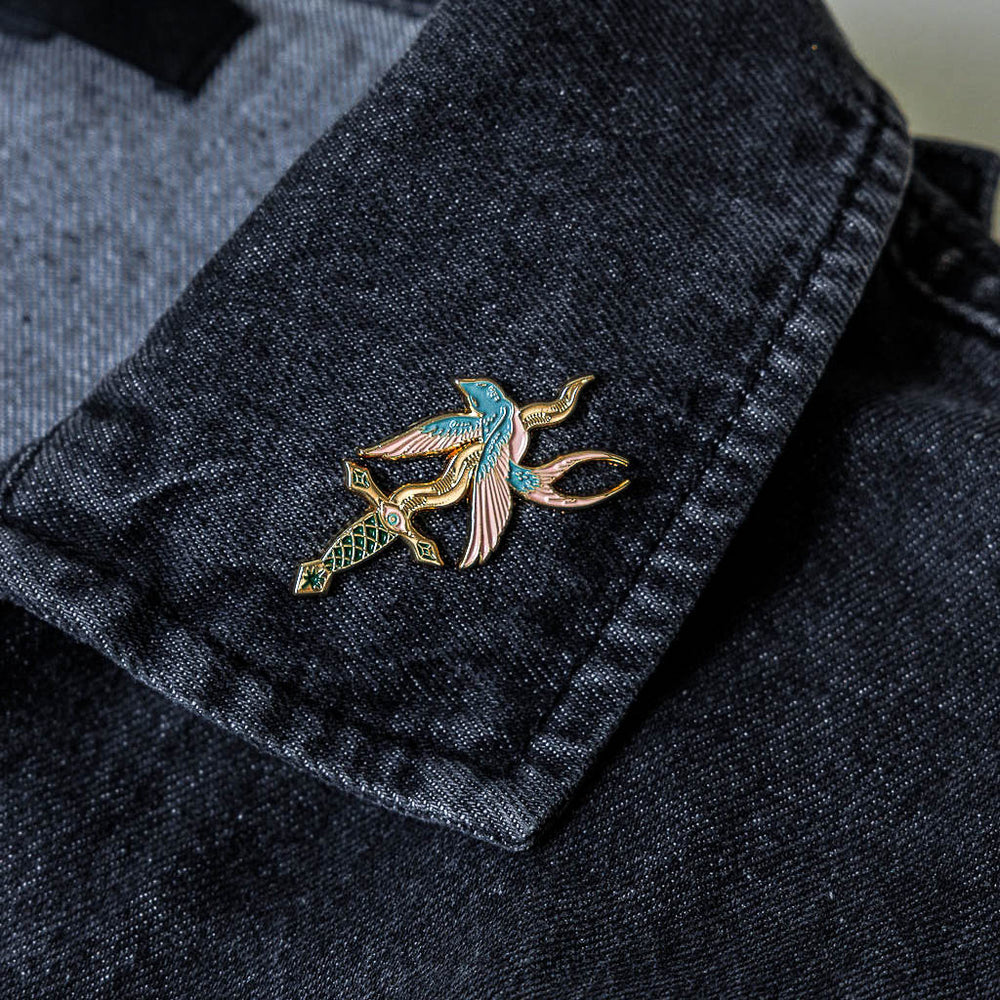 A cool lapel pin of a bird stabbed by a knife for edgy, rock and roll fashion. 