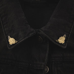 A white rose collar pin set on the lapels of a denim jacket for elegant botanical style.