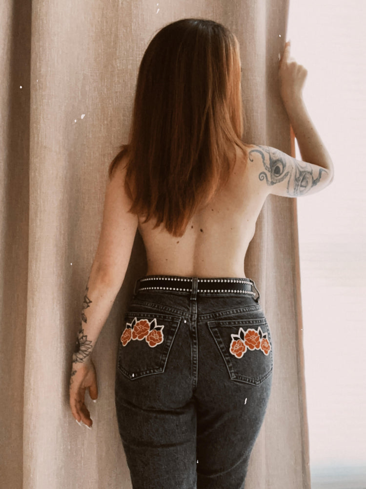 A woman wearing patches on the pockets of her jeans for rock n' roll fashion. 