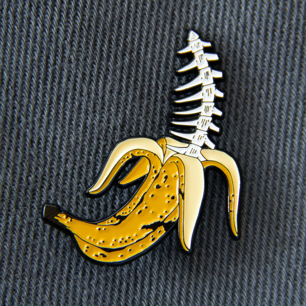 A funny enamel pin of a banana peel with bones inside of it for unisex street fashion.