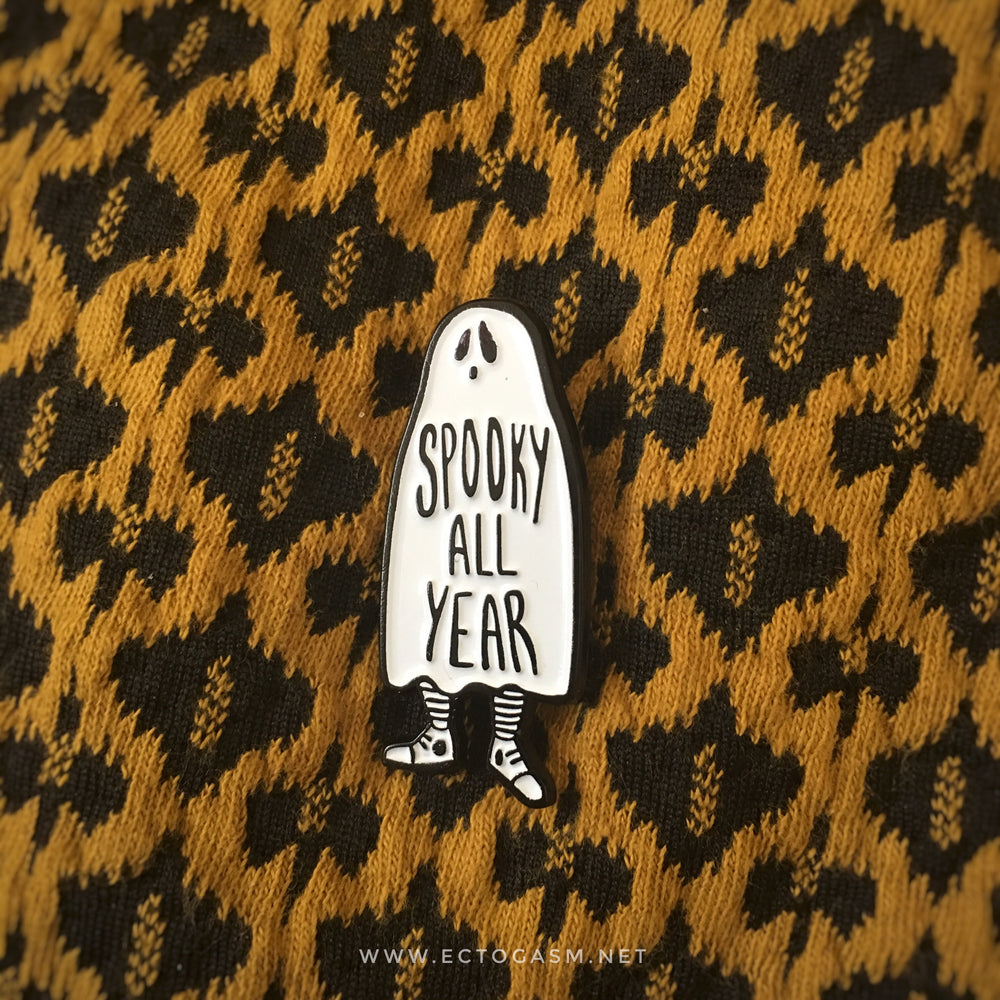 An enamel pin of a ghost that says, "Spooky All Year" on a dress for witch fashion. 