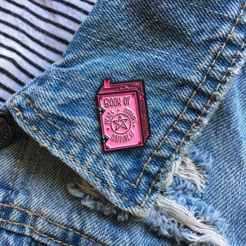 A creepy cute, pink badge of a witch's spell book for pastel goth fashion. 