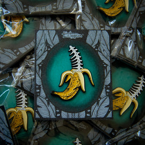 A spooky lapel pin of a banana with bones inside it.
