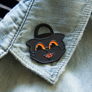 A retro black cat enamel pin on the lapel of a denim jacket for fall fashion. 